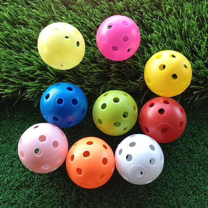 Hollow plastic golf practice ball in orange colour on indoor surface
