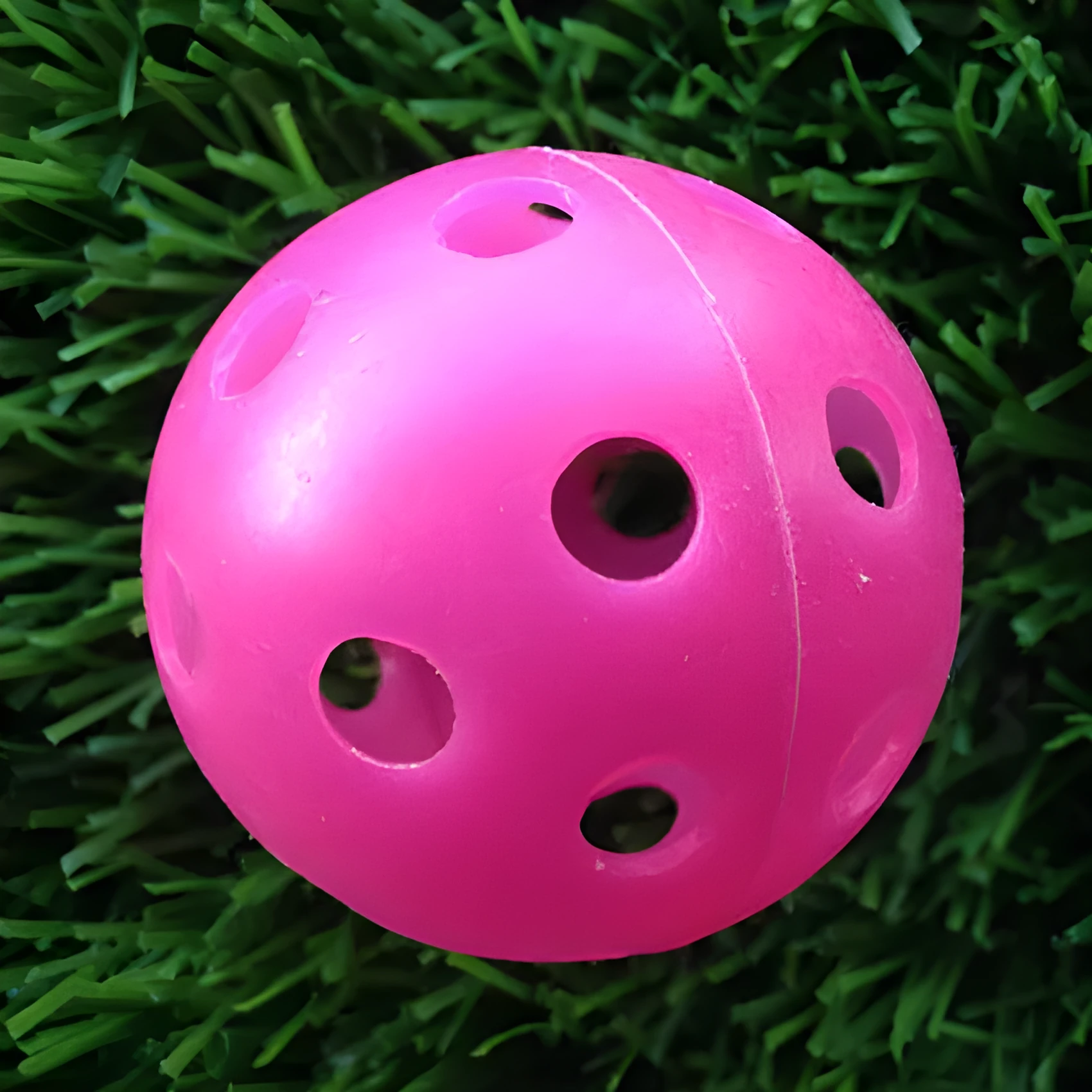 Hollow plastic golf practice ball in orange colour on indoor surface