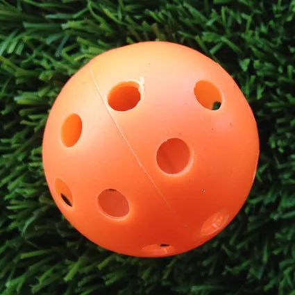 Hollow plastic golf practice ball in orange colour on indoor surface