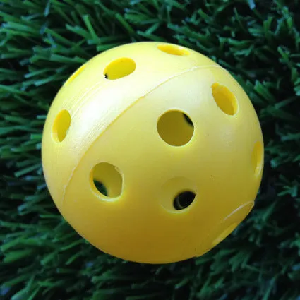 Hollow plastic golf practice ball in orange colour on indoor surface