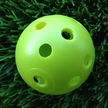 Hollow plastic golf practice ball in orange colour on indoor surface