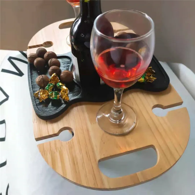Creative multifunctional white wood wine glass rack tray with bottle holder handle holding four wine glasses and a bottle on a picnic table