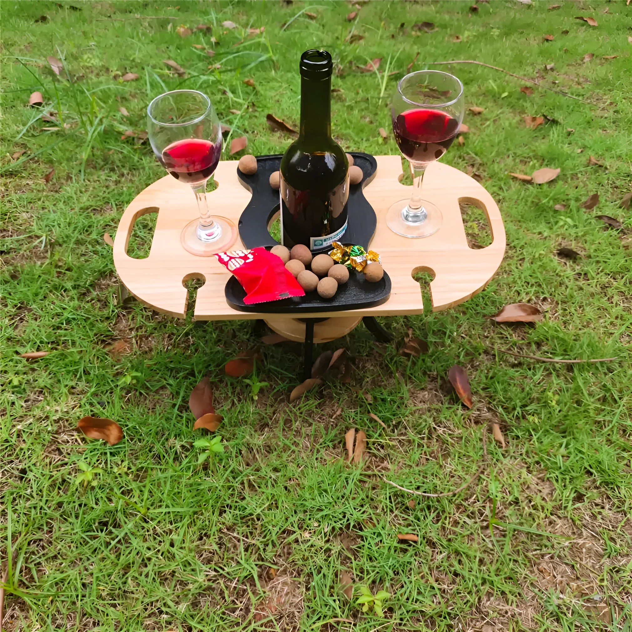 Creative multifunctional white wood wine glass rack tray with bottle holder handle holding four wine glasses and a bottle on a picnic table