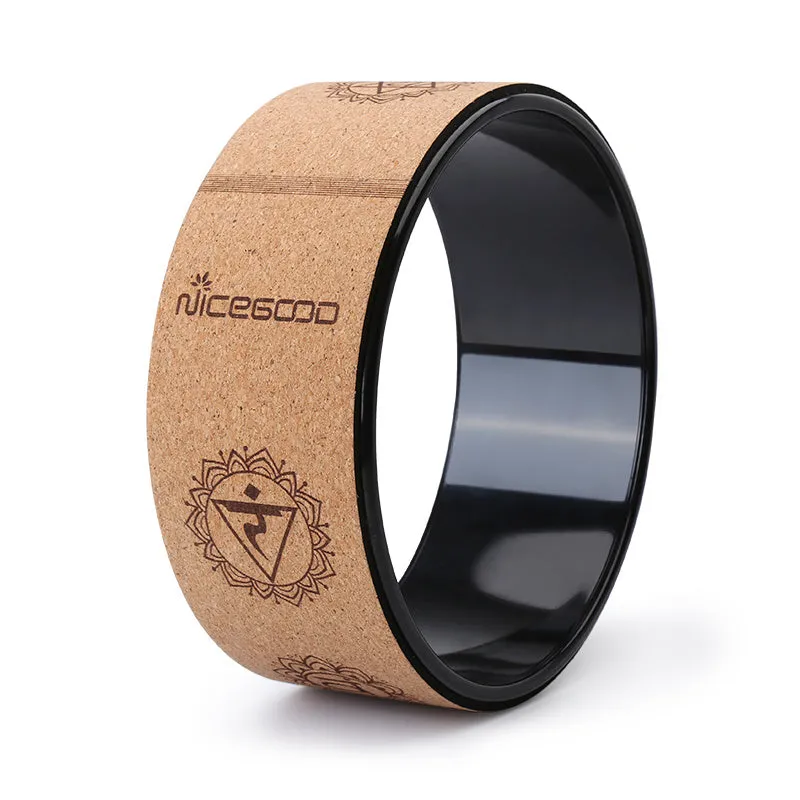 Cork yoga wheel in classic black, 32cm diameter, on a yoga mat in a home studio