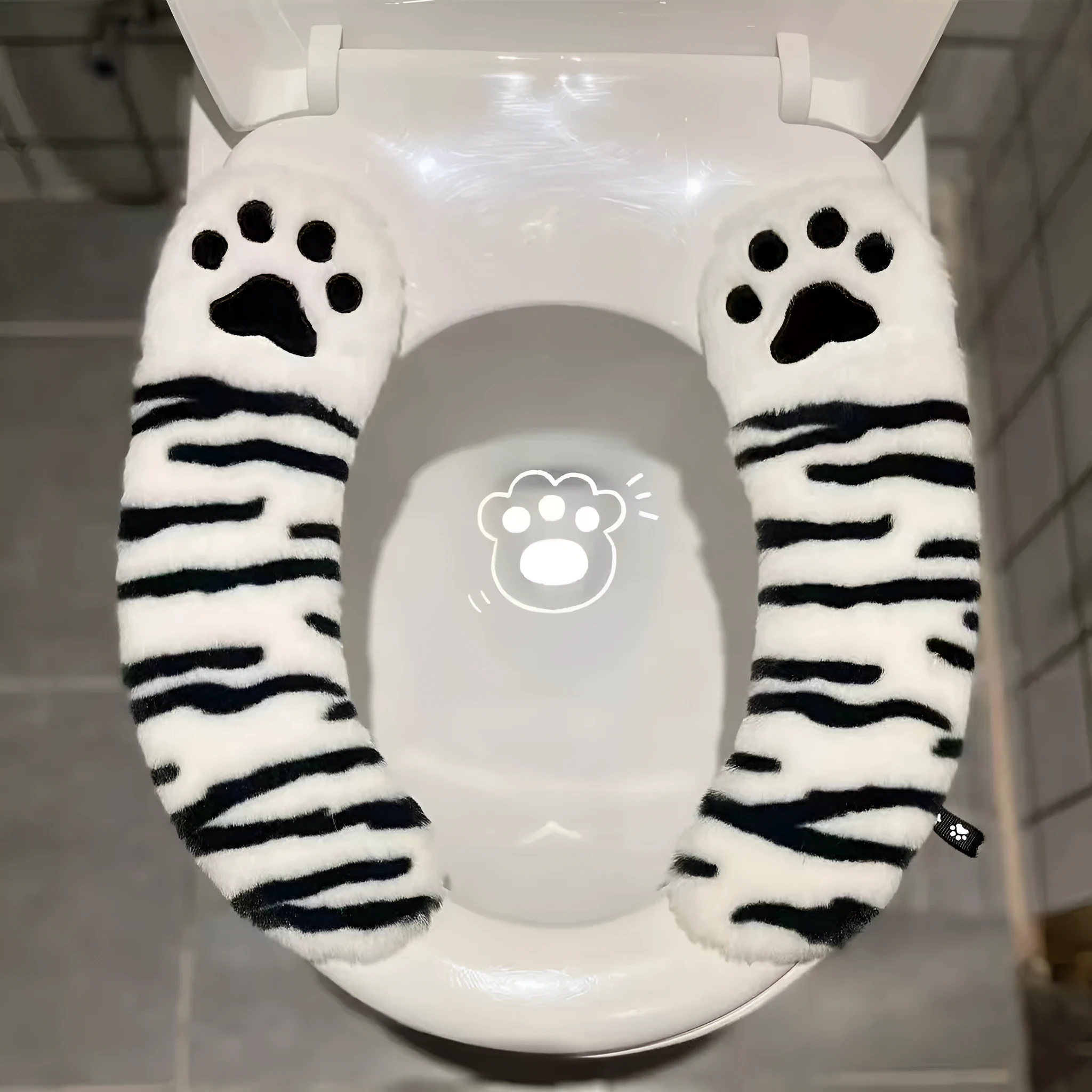 Plush toilet seat cushion with adhesive Velcro fastener in black and white stripes for bathroom use