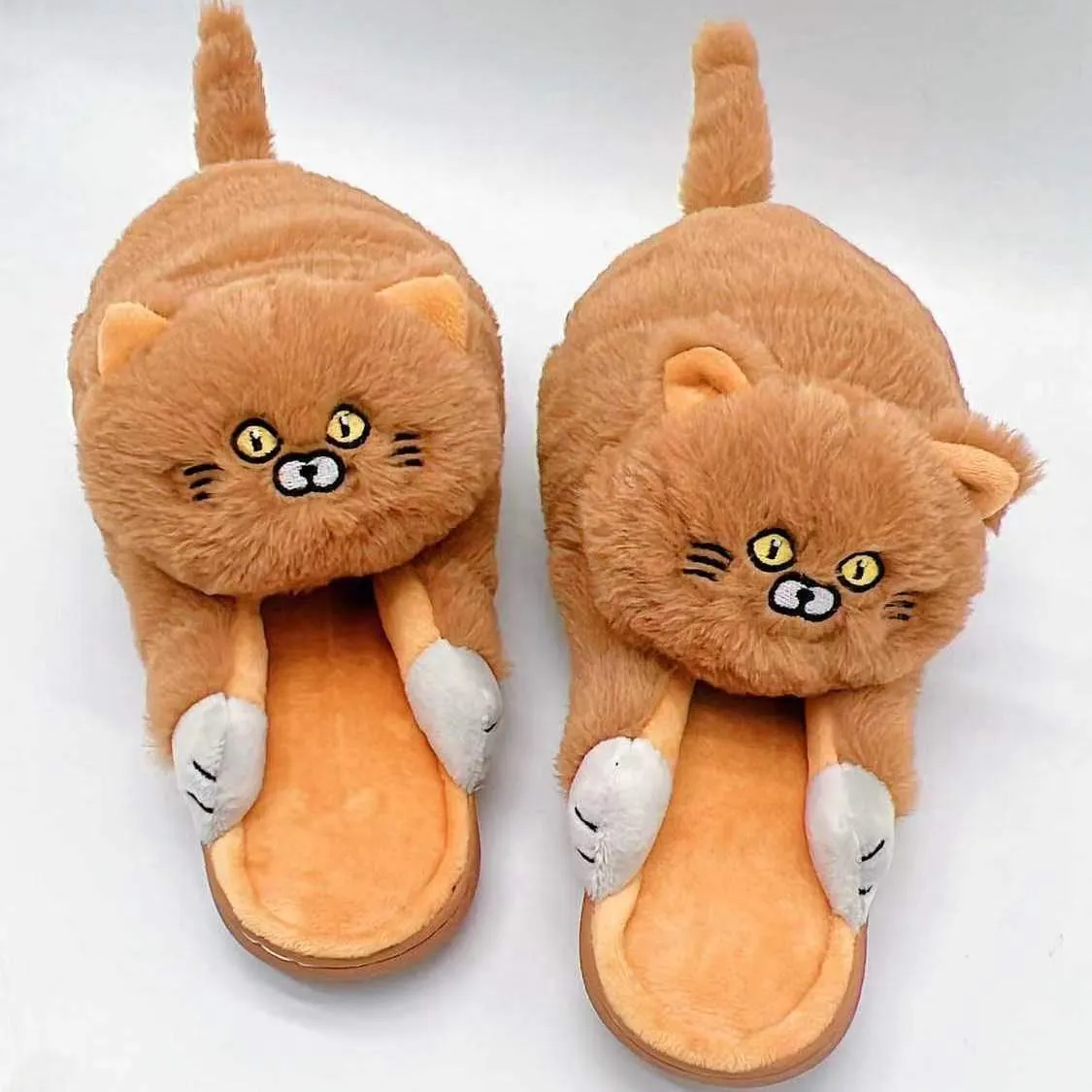 Pair of beige cat hug plush cotton slippers with non-slip sole on a soft floor