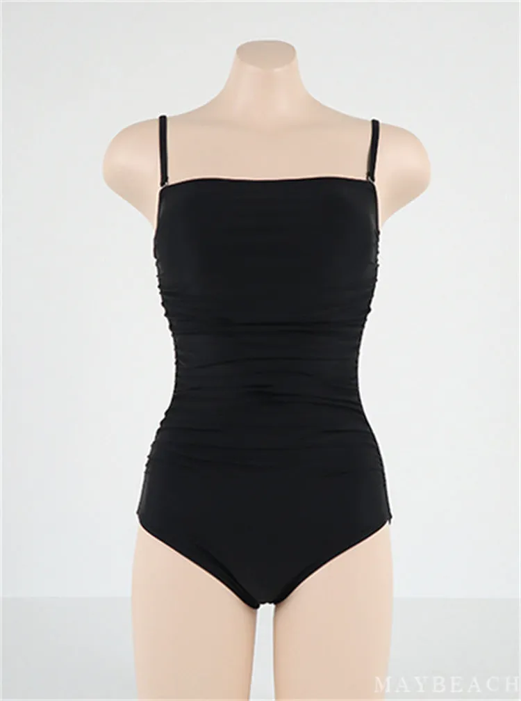 Sling style one-piece swimsuit with belly pleats in black, blue, white, or yellow on a model