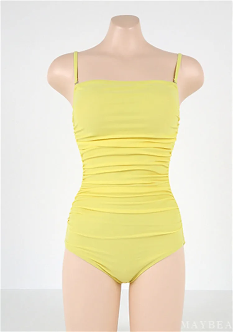 Sling style one-piece swimsuit with belly pleats in black, blue, white, or yellow on a model