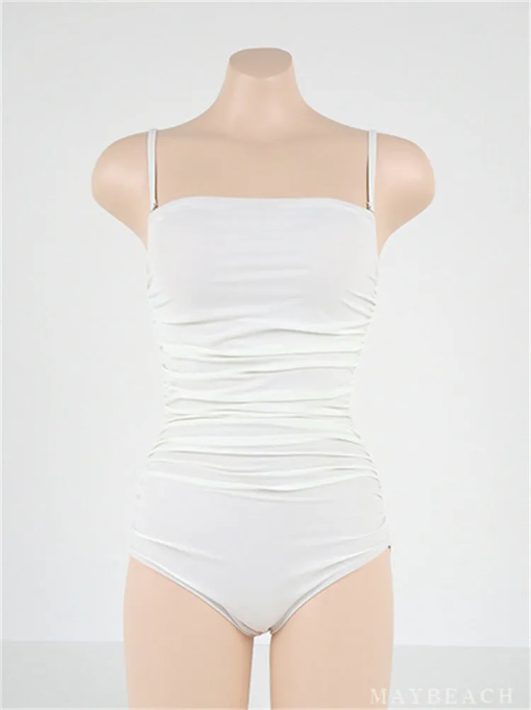 Sling style one-piece swimsuit with belly pleats in black, blue, white, or yellow on a model