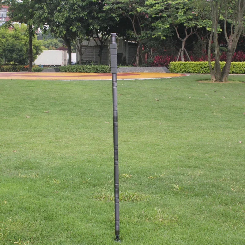 Dark grey aluminium trekking pole with tactical knife and screwdriver accessories on a hiking trail