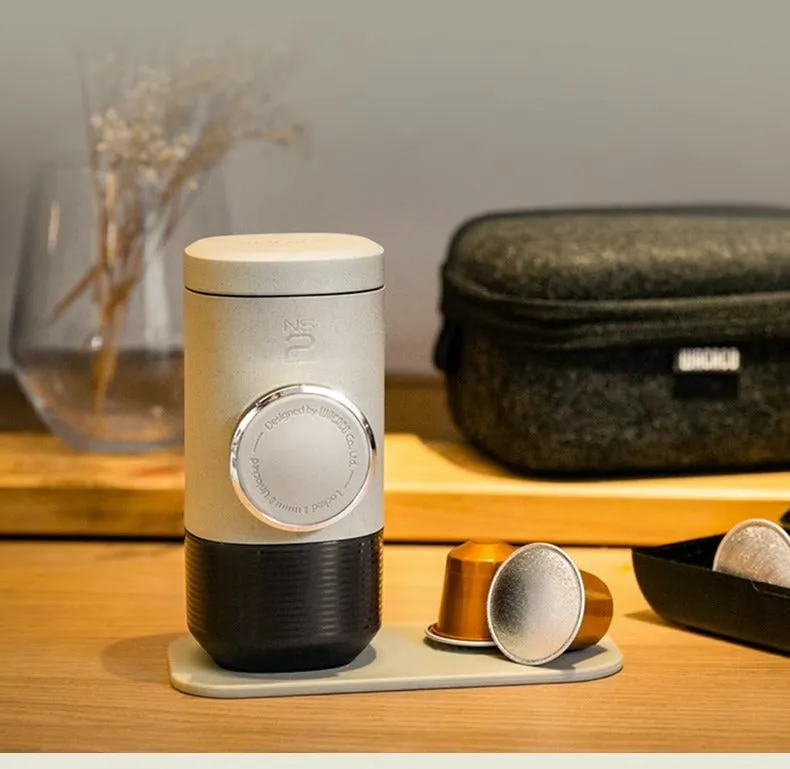 Manual espresso portable capsule coffee machine in olive gray with resin body, 129x70x60mm, on outdoor background