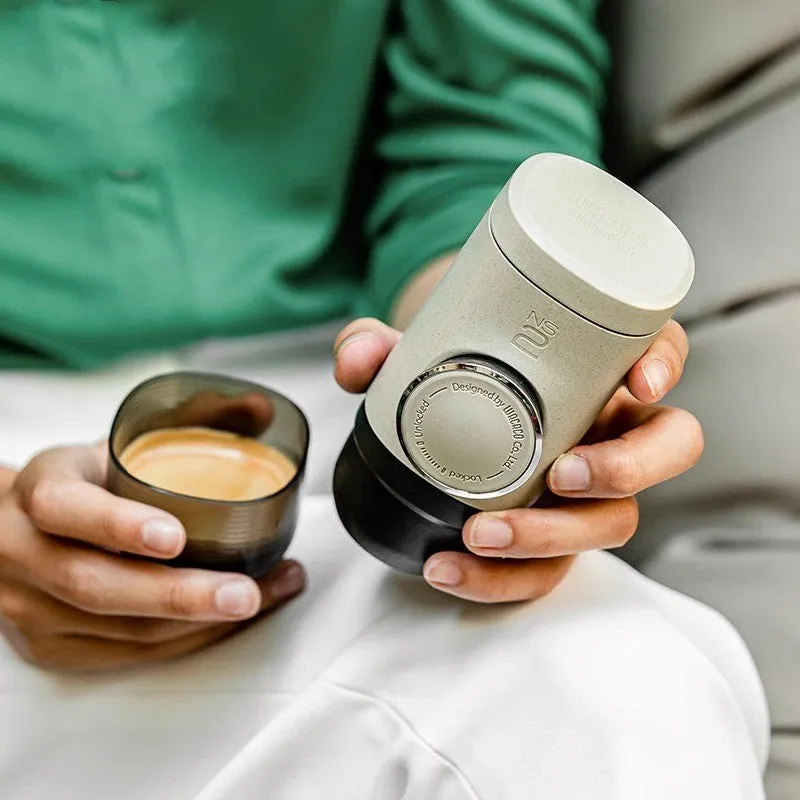 Manual espresso portable capsule coffee machine in olive gray with resin body, 129x70x60mm, on outdoor background