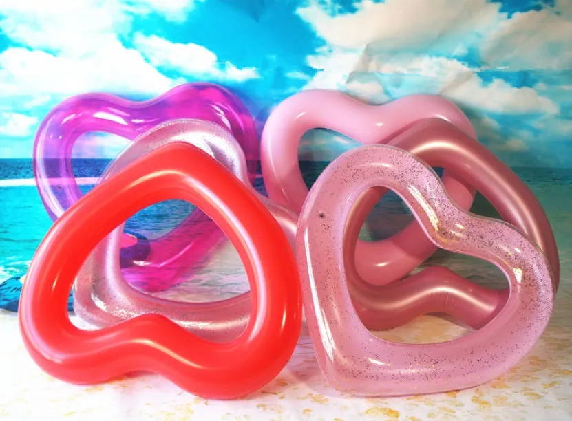 Oversized 120cm heart shaped swim ring in pink floating on water, adult outdoor pool toy