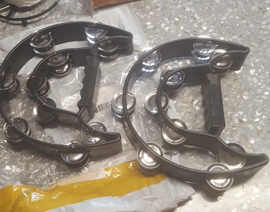 Double moon shaped black plastic tambourine with handle, 25 x 20 cm, on a light background