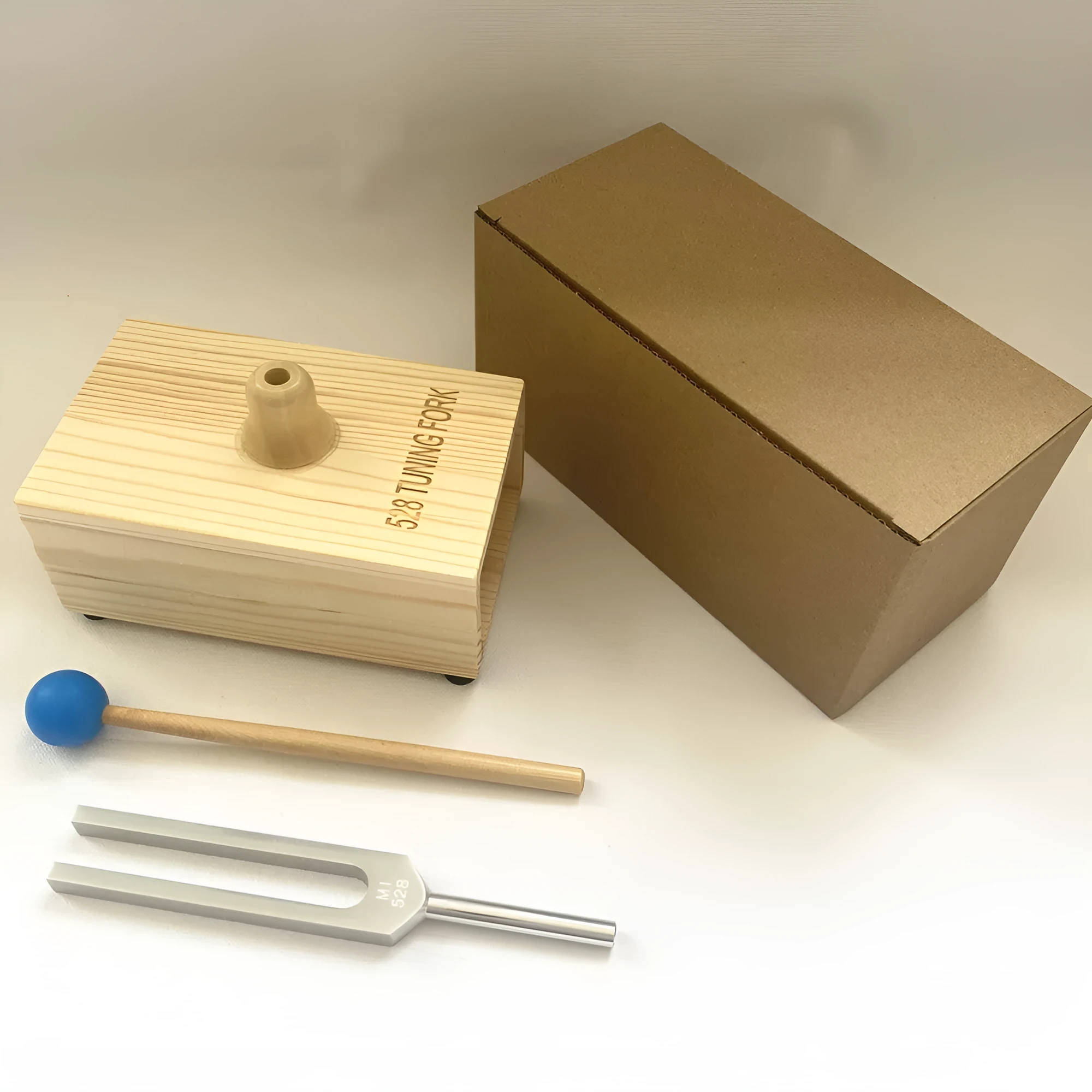 Aluminium alloy 432Hz tuning fork and portable speaker kit on a kraft paper box.