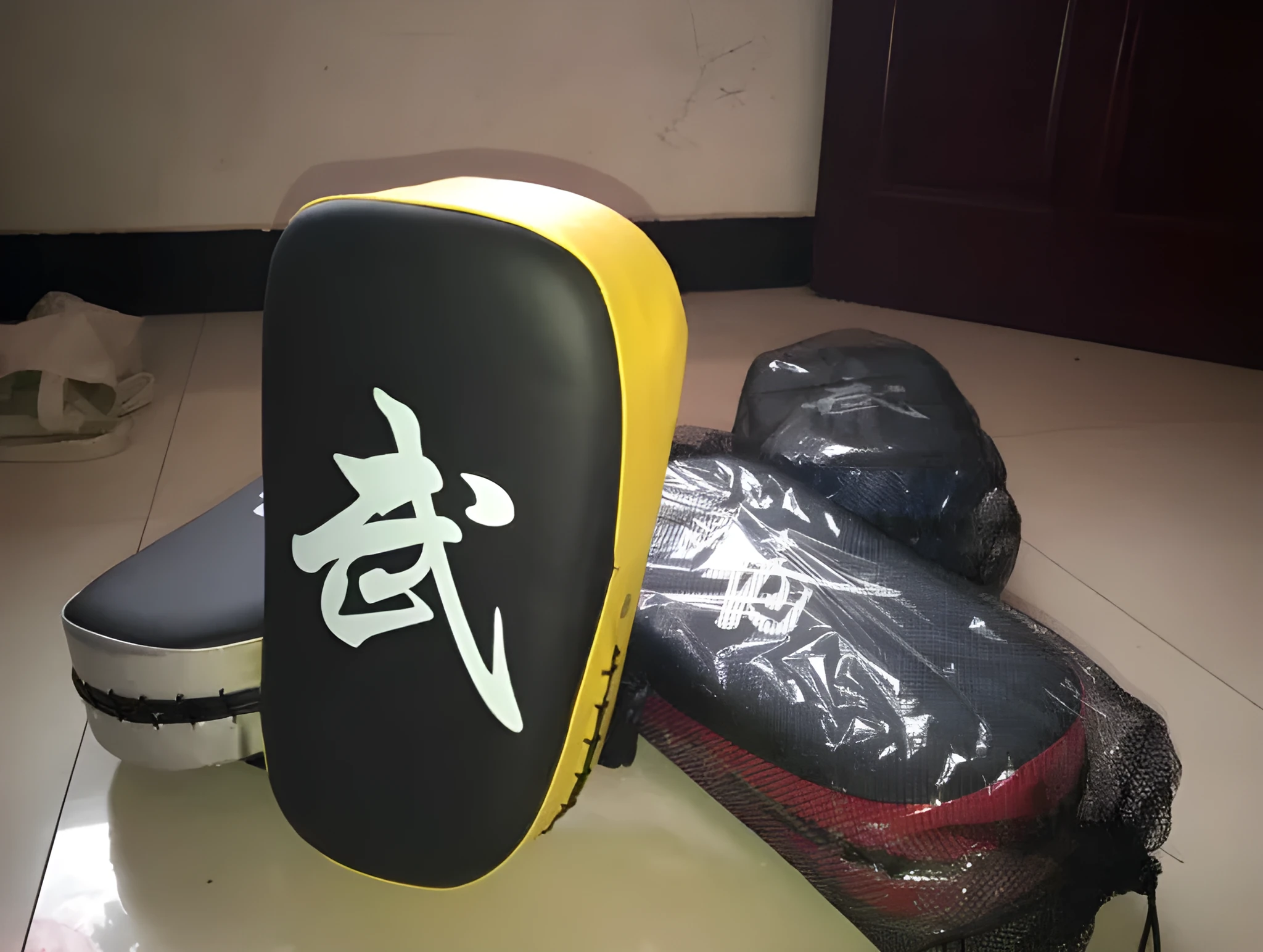 Muay Thai foot target pad in PU leather with black and blue colour scheme showing curved face and Velcro strap