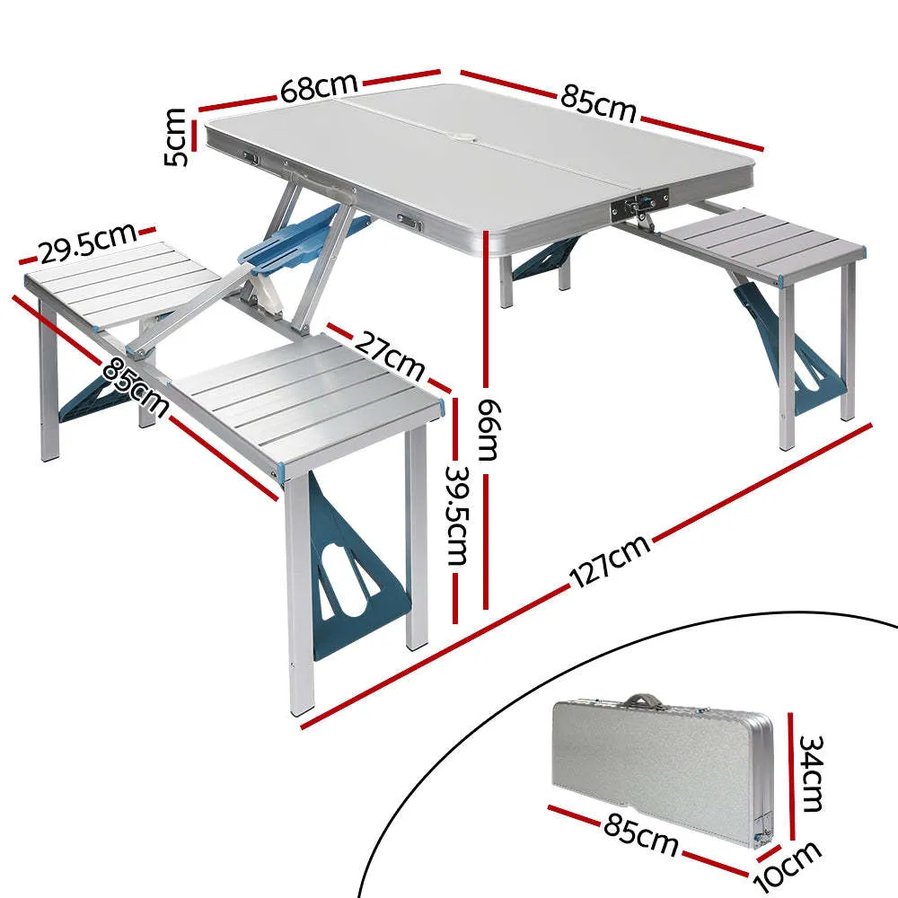 Outdoor folding table and chair set in aluminium alloy with four chairs, expanded on grass, silver gray colour, showing 85.5cm desktop and umbrella hole
