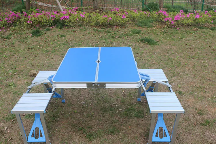 Outdoor folding table and chair set in aluminium alloy with four chairs, expanded on grass, silver gray colour, showing 85.5cm desktop and umbrella hole