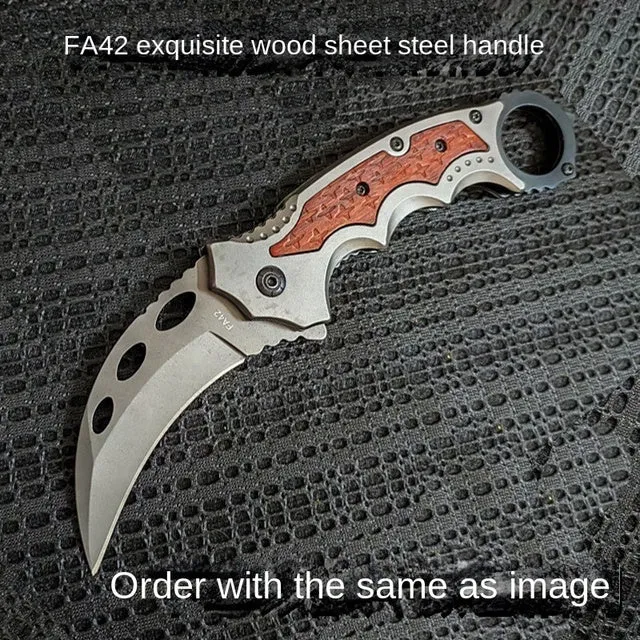 Folding claw knife with grey titanium blade and sour branch wood handle on a surface