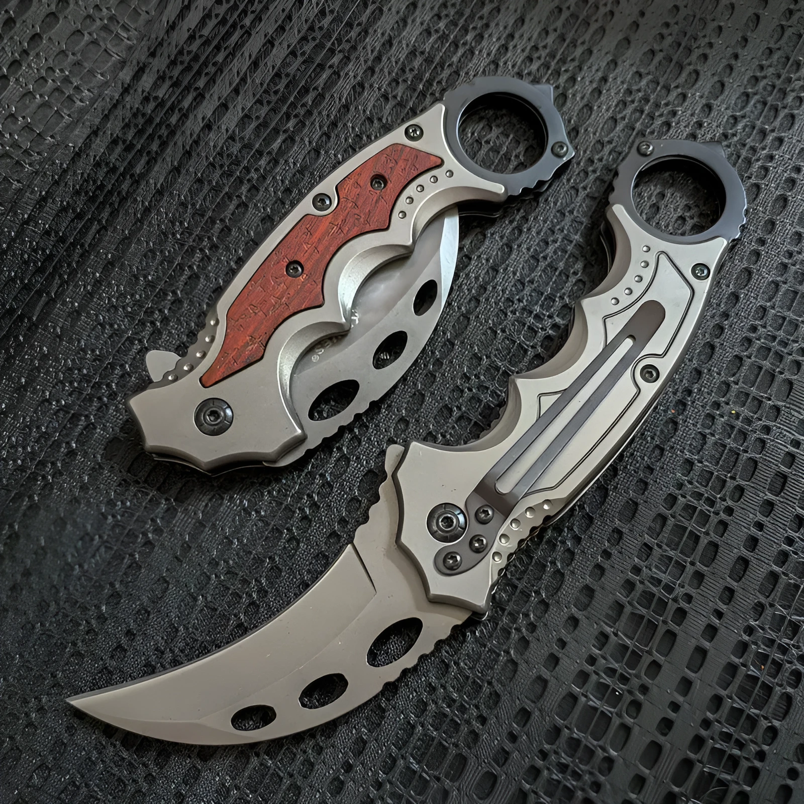 Folding claw knife with grey titanium blade and sour branch wood handle on a surface
