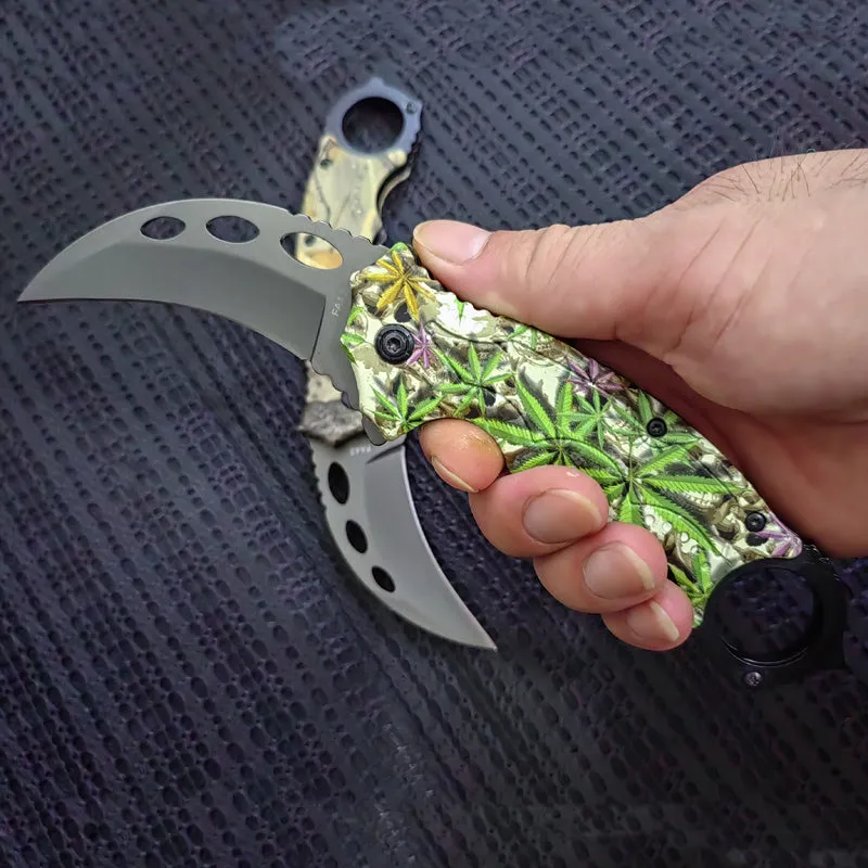 Folding claw knife with grey titanium blade and sour branch wood handle on a surface