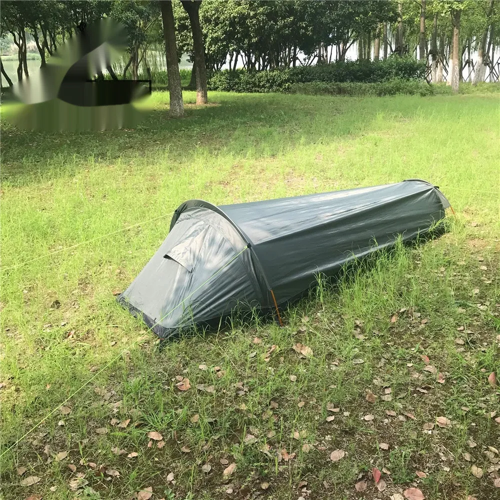 Single person sleeping bag tent in army green set up outdoors, showing rain fly and aluminium rod poles.