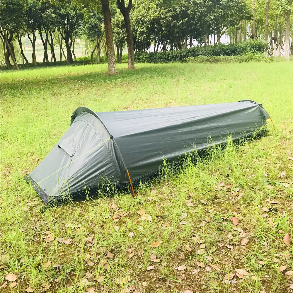 Single person sleeping bag tent in army green set up outdoors, showing rain fly and aluminium rod poles.