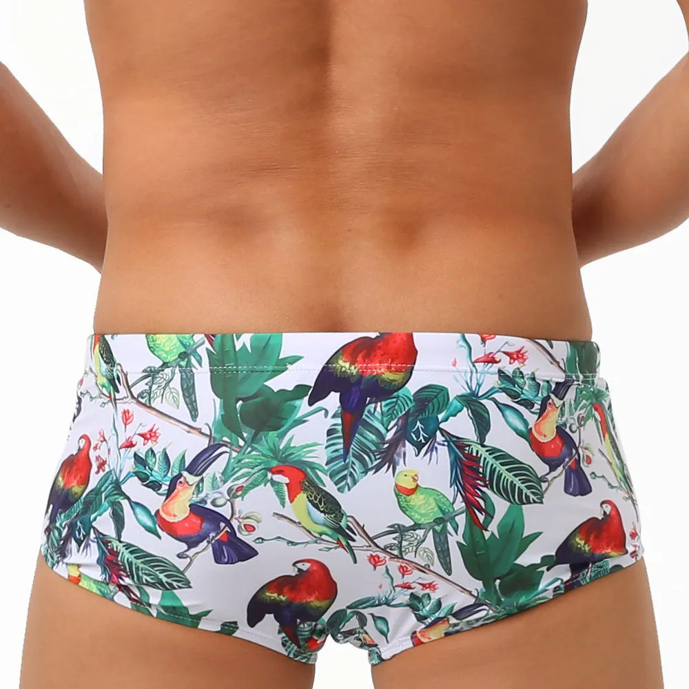 Men's blue swimming trunks with a detailed floral and bird print pattern, small boxer style