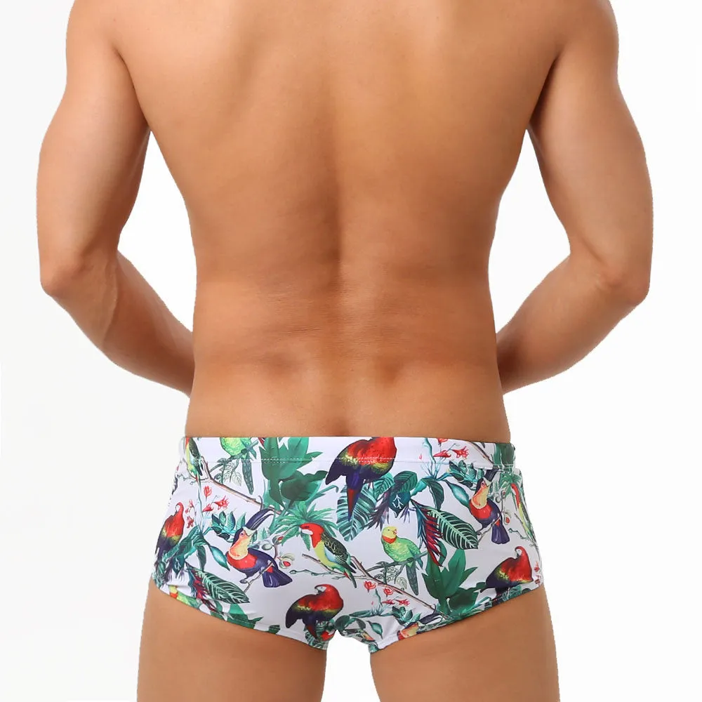 Men's blue swimming trunks with a detailed floral and bird print pattern, small boxer style