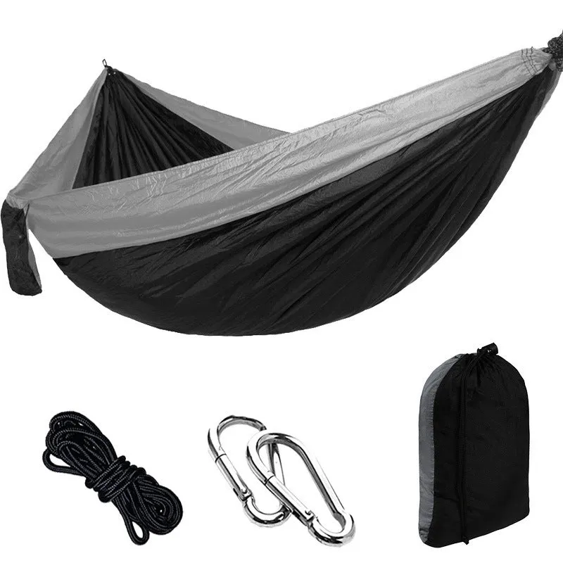 Parachute cloth camping hammock in 210T nylon hanging between trees with included ropes and buckles
