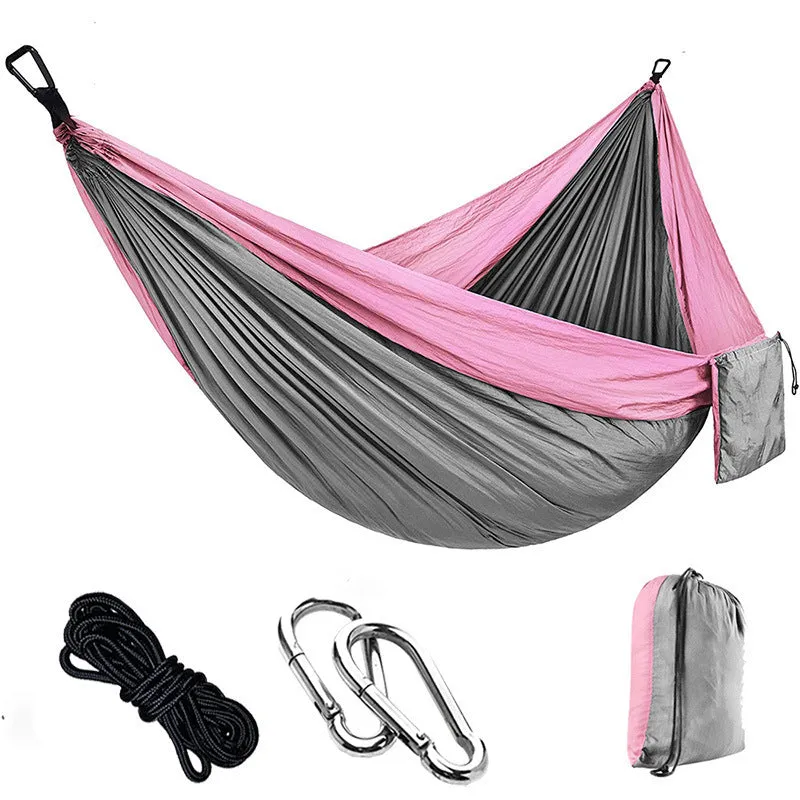 Parachute cloth camping hammock in 210T nylon hanging between trees with included ropes and buckles
