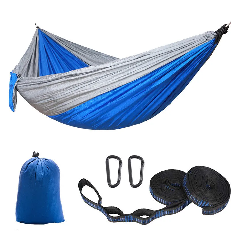 Parachute cloth camping hammock in 210T nylon hanging between trees with included ropes and buckles