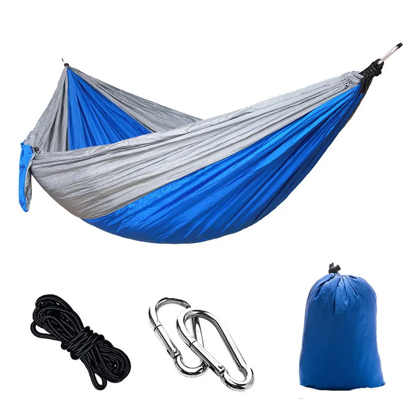 Parachute cloth camping hammock in 210T nylon hanging between trees with included ropes and buckles