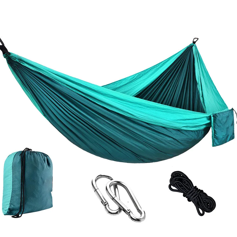 Parachute cloth camping hammock in 210T nylon hanging between trees with included ropes and buckles