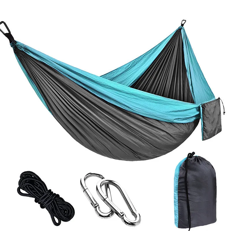 Parachute cloth camping hammock in 210T nylon hanging between trees with included ropes and buckles