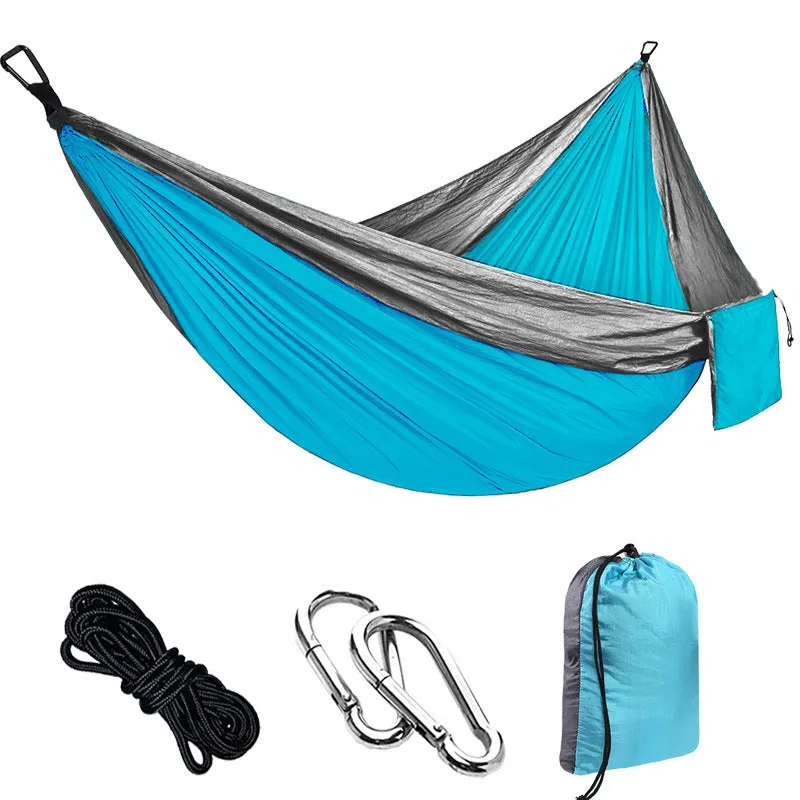Parachute cloth camping hammock in 210T nylon hanging between trees with included ropes and buckles