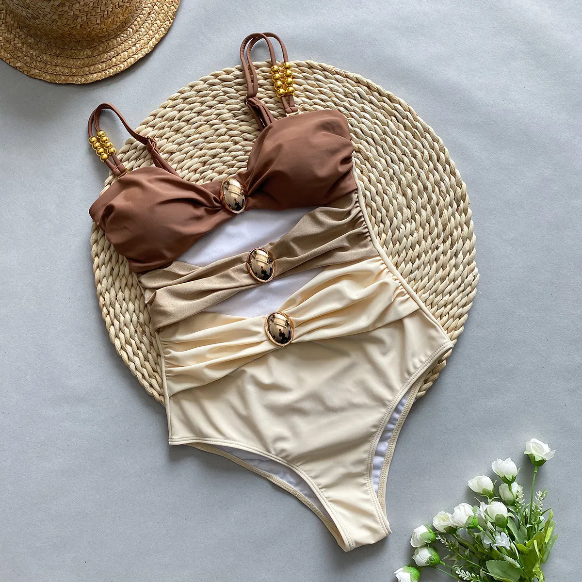 Women's brown one-piece swimsuit with a matching detachable beige skirt laid flat.