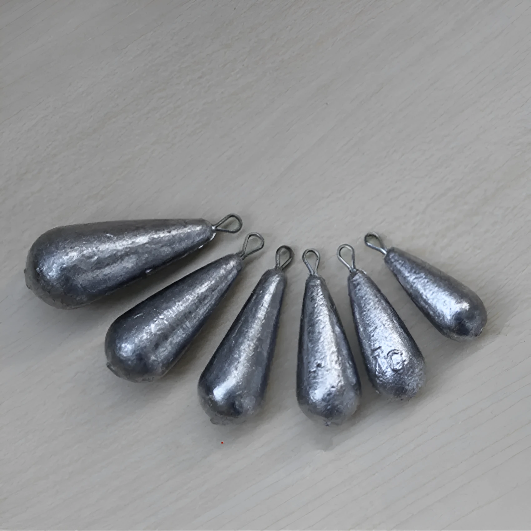 Set of drop-shaped lead fishing sinkers and a Tongxin sinker in various weights from 20g to 50g.