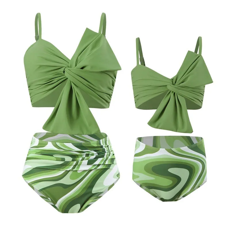 Women's orange nylon bikini set with large white bow print, showing top and swim trunks.