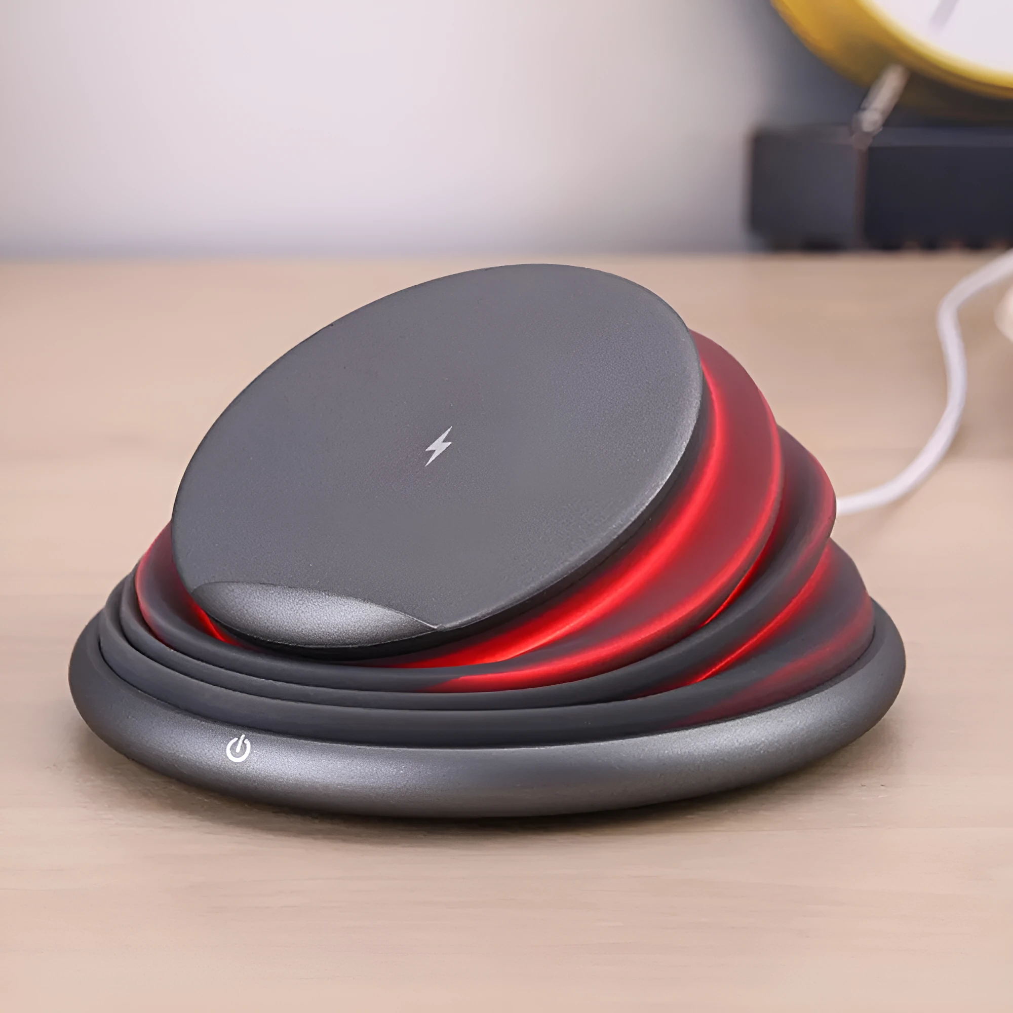 Grey wireless charger pad with silicone surface on a desk, 138mm square shape