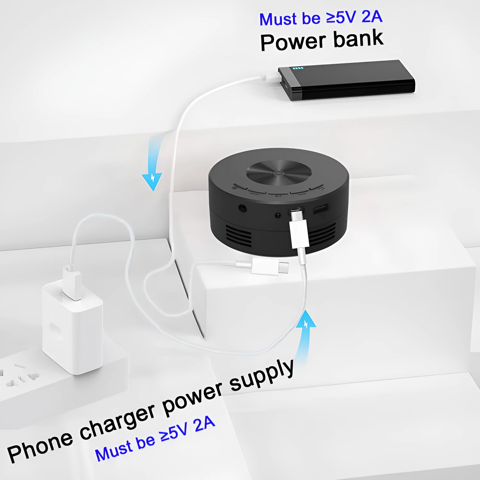 Black mini portable home projector for children next to a mobile phone.