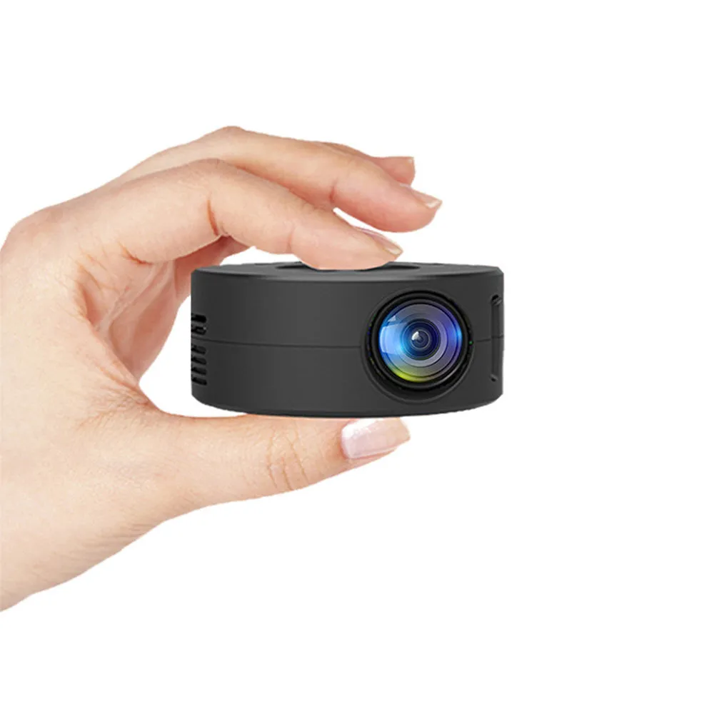 Black mini portable home projector for children next to a mobile phone.
