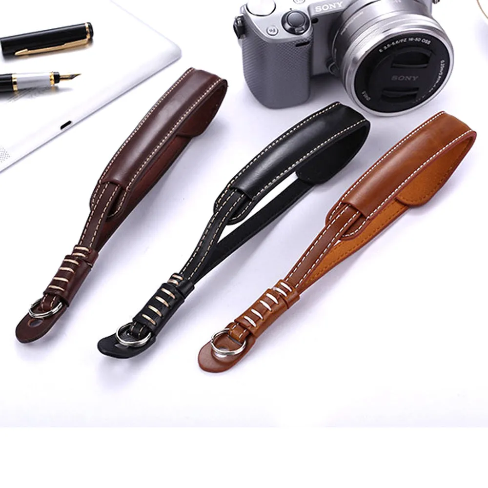 Adjustable black leather camera wrist strap attached to a digital camera body