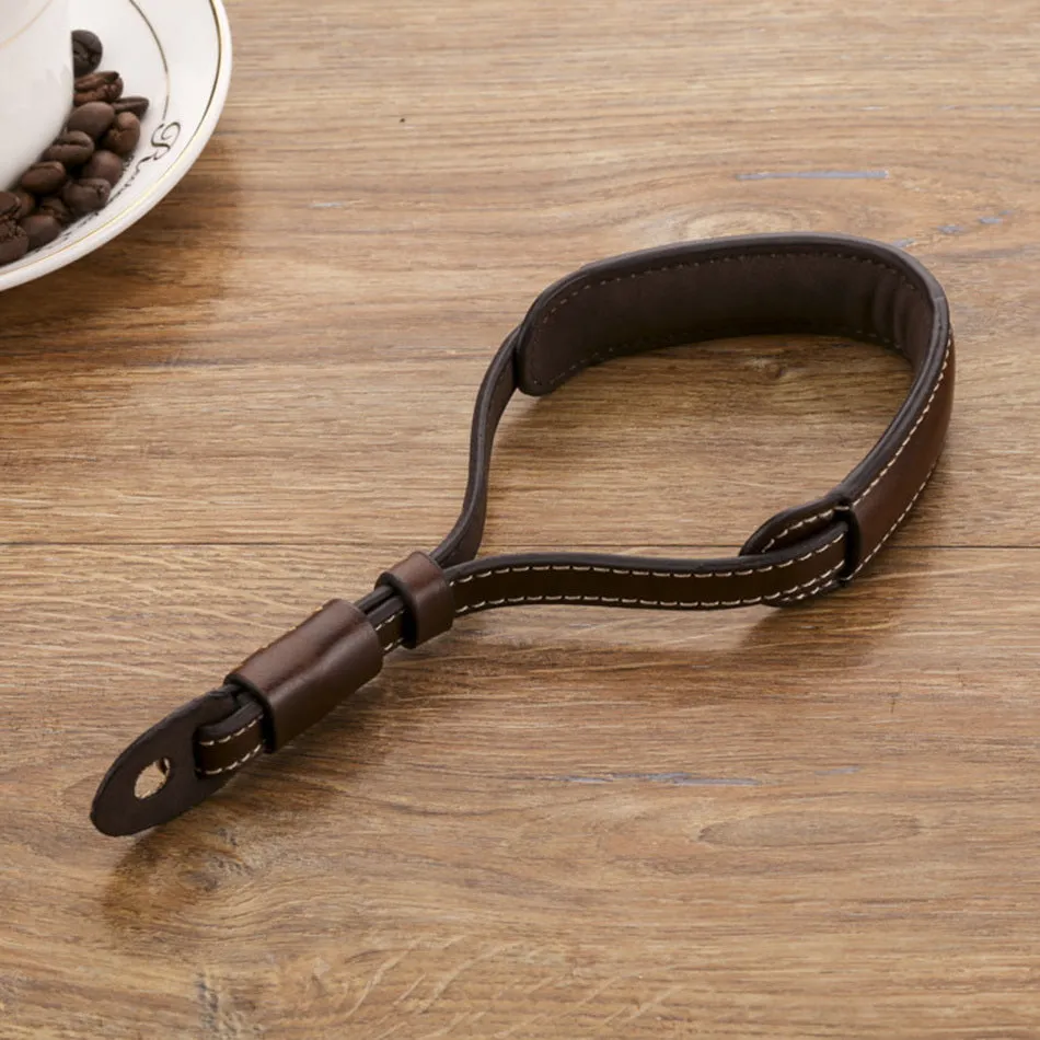 Adjustable black leather camera wrist strap attached to a digital camera body