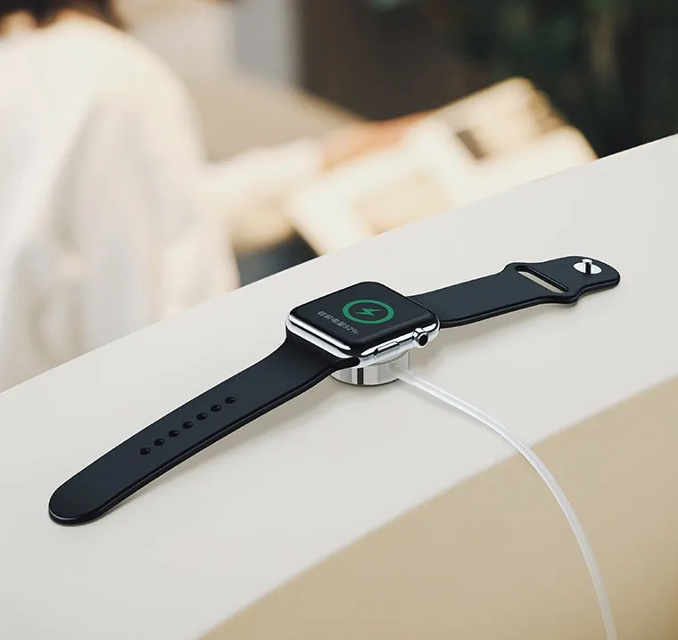 White metal Apple Watch wireless charger with 1m USB cable on a table