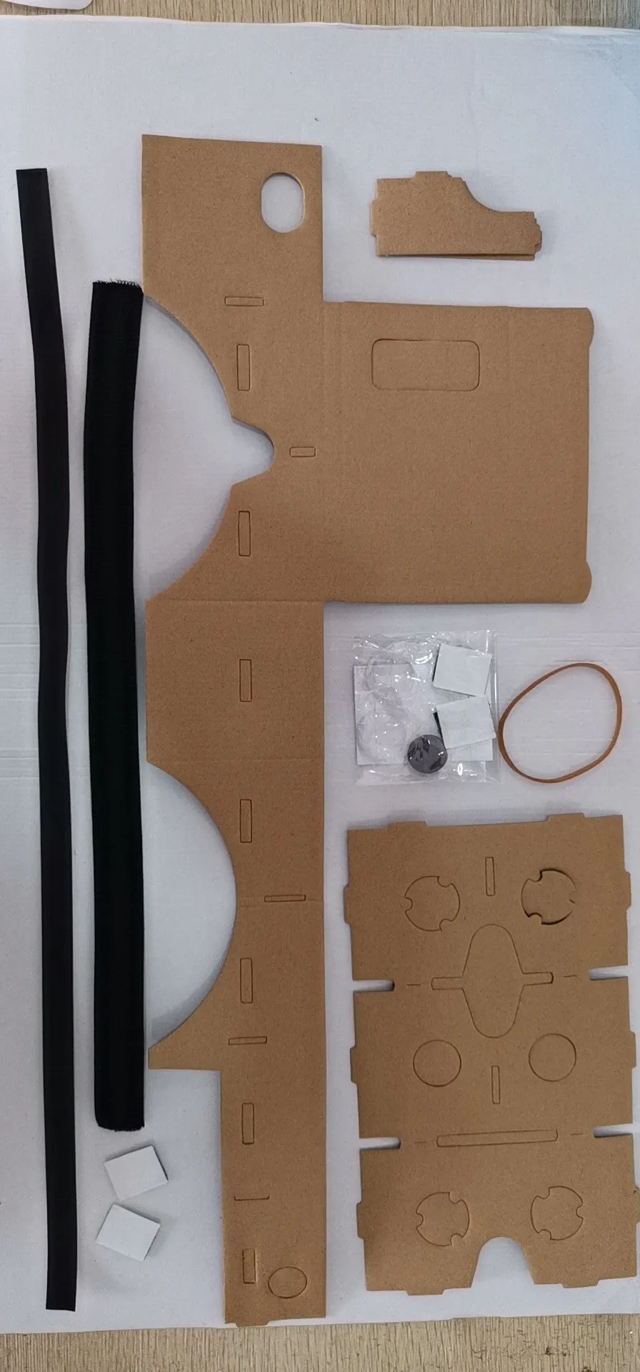 Foldable pink and white VR cardboard glasses headset for smartphones with adjustable strap and 3D lenses.