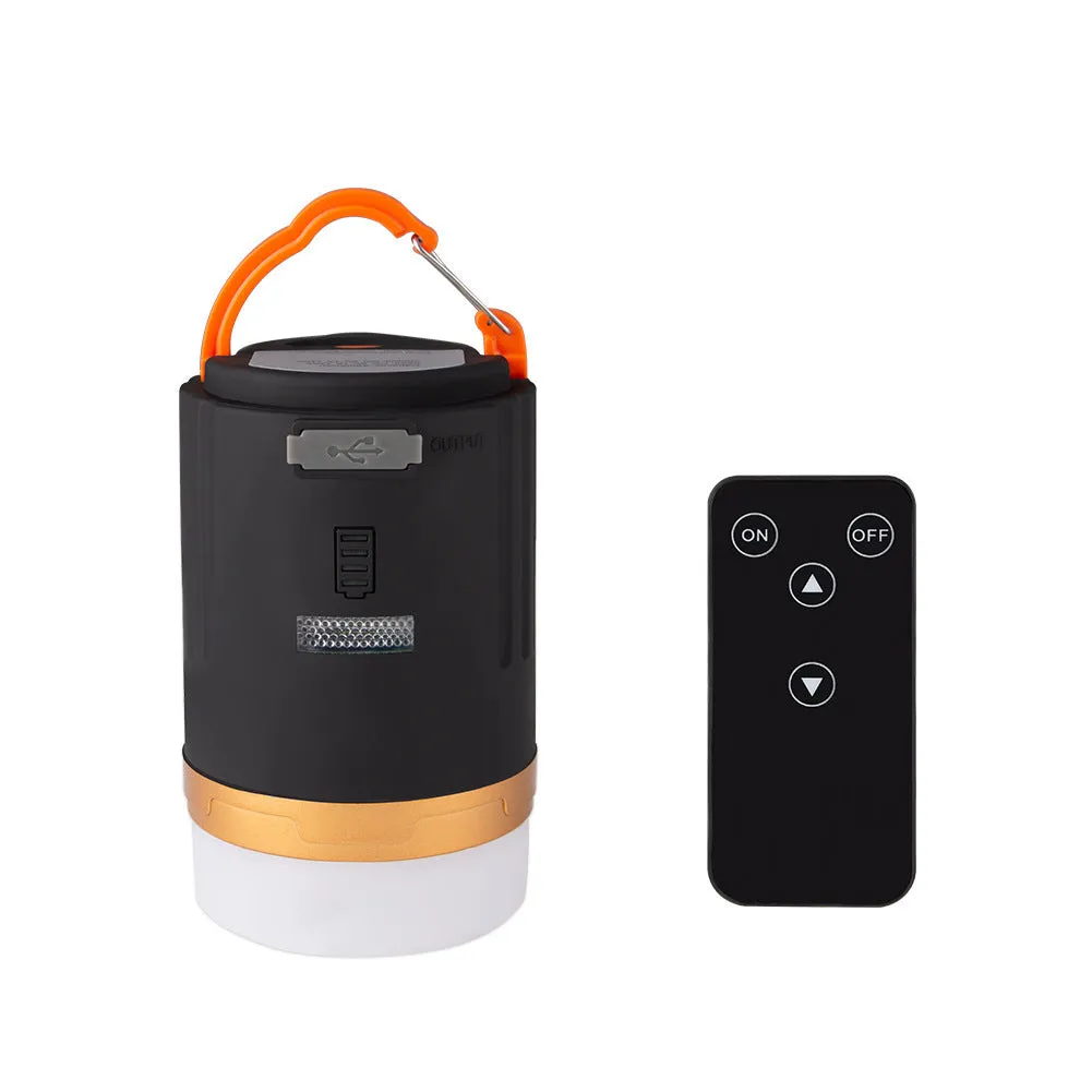 Black rechargeable LED camping light with hanging hook and remote control on a table