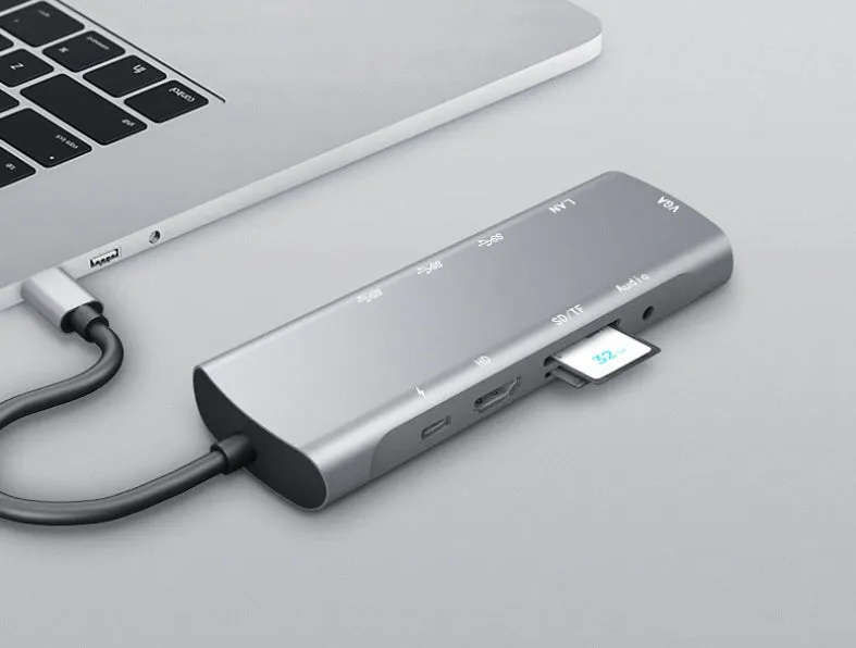 Grey aluminium USB-C docking station with multiple ports including HDMI, VGA, and USB, showing its 140mm attached cable.
