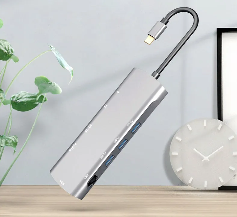 Grey aluminium USB-C docking station with multiple ports including HDMI, VGA, and USB, showing its 140mm attached cable.