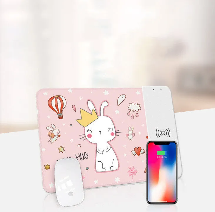 Black wireless charging mouse pad with RGB lighting edge and a cartoon design, shown on a desk.